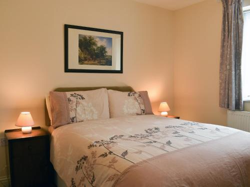 a bedroom with a bed with two lamps on tables at Red Lion Cottage in Chatteris