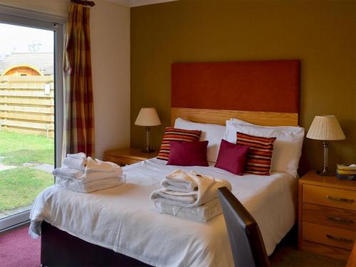 una camera da letto con un letto e asciugamani di Holly Lodge ad Aviemore