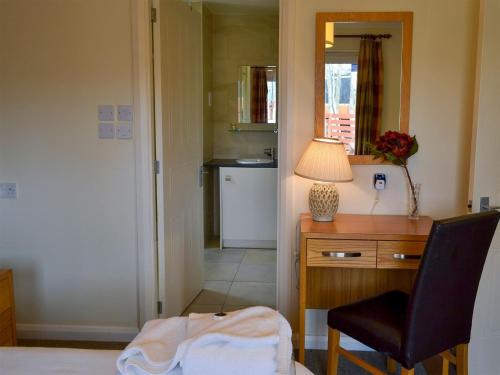 um quarto com uma secretária, uma cadeira e um candeeiro em Holly Lodge em Aviemore