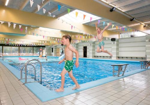 Dois rapazes a saltar para uma piscina. em Recreatiepark de Koornmolen em Zevenhuizen