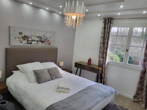 une chambre avec un lit et un lustre dans l'établissement Villa Alice, à Blérancourt