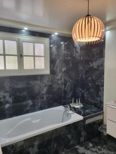 a bathroom with a tub and a black marble wall at Villa Alice in Blérancourt