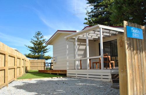 a small white house with a wooden fence at Waikanae Beach TOP 10 Holiday Park in Gisborne