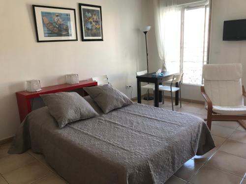 Schlafzimmer mit einem Bett, einem Schreibtisch und einem Stuhl in der Unterkunft Studio 2ème étage vue sur Quai et Mont Saint Clair in Sète