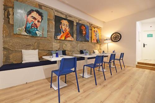 a room with tables and chairs and paintings on the wall at FLH Porto Downtown GuestHouse in Porto