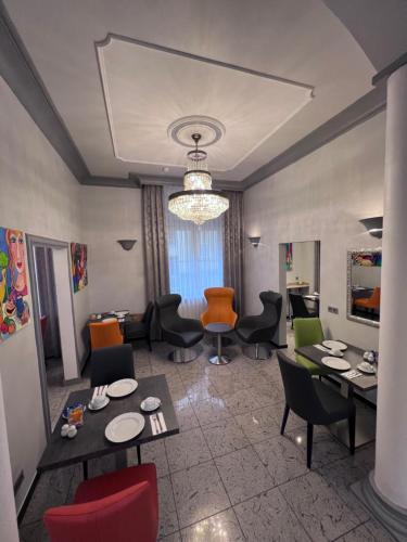 a living room with tables and chairs and a chandelier at Gästehaus Kral in Erlangen