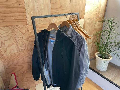 uma prateleira com camisas e casacos pendurados numa parede em ゲストハウス 西村サイクル（24C） em Izume