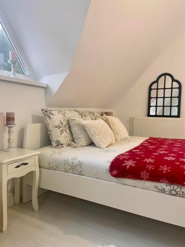 a white bedroom with a bed with a red blanket at Farmhouse Dzeni in Vlasic