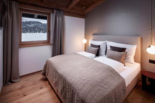 Un dormitorio con una cama grande y una ventana en Alpin Residenzen Buchensteinwand St. Ulrich by Alpina-Holiday, en Sankt Ulrich am Pillersee