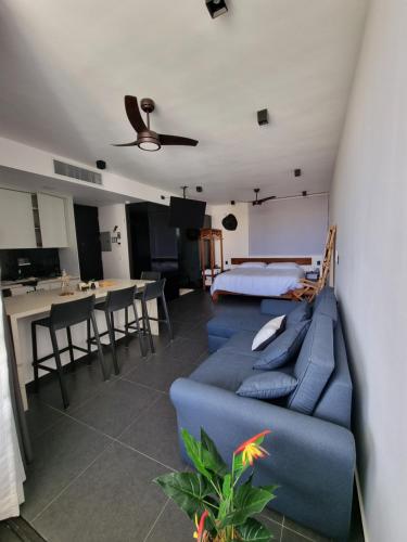 uma sala de estar com um sofá azul e uma cozinha em Exclusivo Departamento de lujo con jacuzzi privado em Tulum