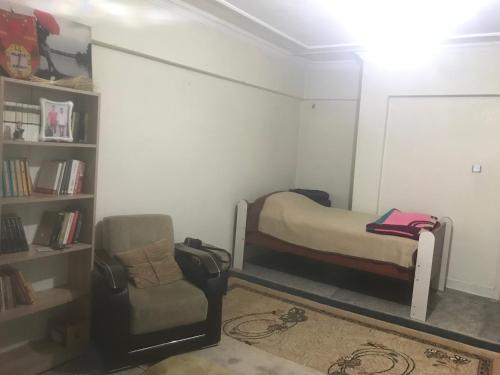 a room with a bed and a chair and a book shelf at House in Kayapınar