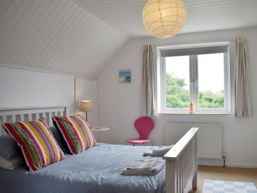 a bedroom with a bed with a window and a pink chair at Lo-tide in Middleton-on-Sea