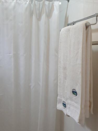 La salle de bains est pourvue d'un rideau de douche blanc et d'une serviette. dans l'établissement Kara O Mula Mulanje, à Mulanje