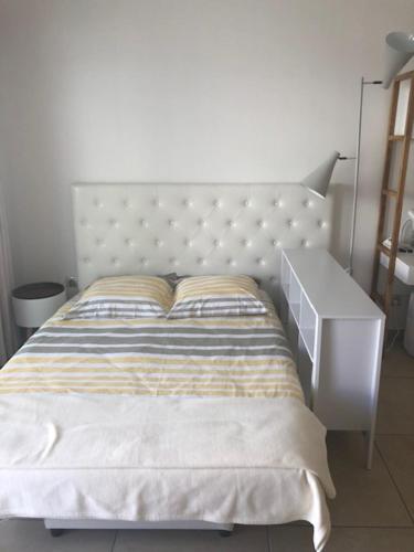 a bed with a white headboard and a night stand at AGENCIA Studio Cannes Maria in Cannes