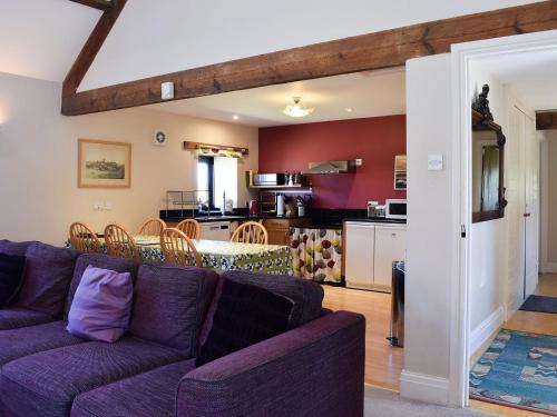 a living room with a purple couch and a kitchen at The Byre in Westerdale