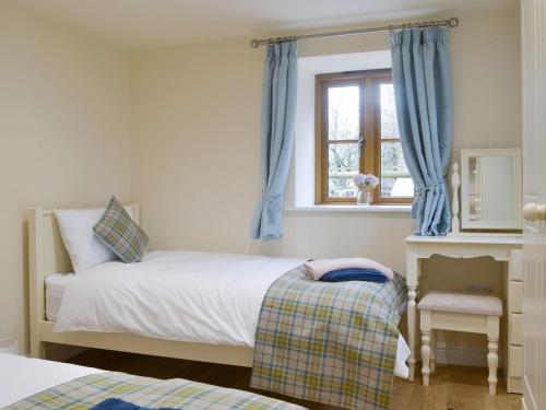 a bedroom with a bed and a window with blue curtains at No, 1 Ash Cottage in Quatt