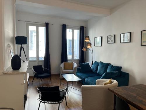 - un salon avec un canapé bleu et des chaises dans l'établissement La Comédie, appart de Charme, à Montpellier