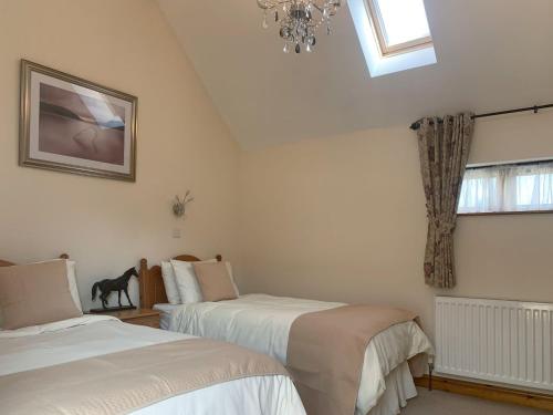 a bedroom with two beds and a window and a chandelier at Stables in North Somercotes
