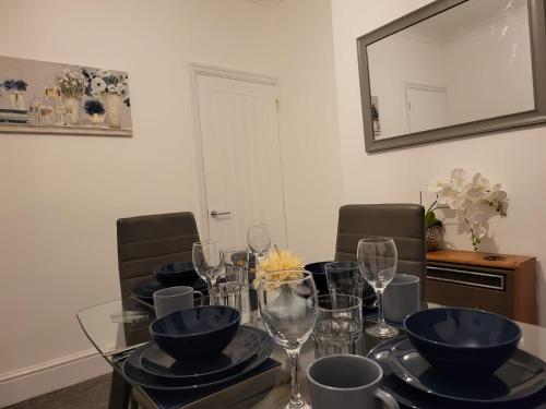 a dining room table with bowls and glasses on it at Homey Bella House in Luton