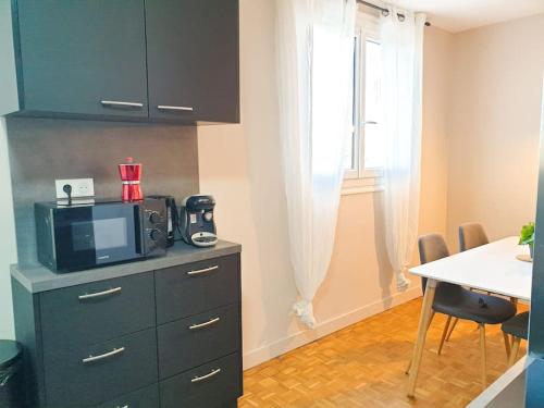 une cuisine avec une table et un four micro-ondes sur une commode dans l'établissement Cosy Mûre 4CH - Stationnement gratuit, à Pau