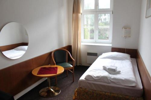 a bedroom with a bed and a chair and a mirror at Hotel Skála in Malá Skála