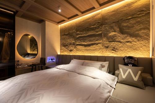 a bedroom with a large bed and a stone wall at Design Hotel W Zip Club in Nagoya