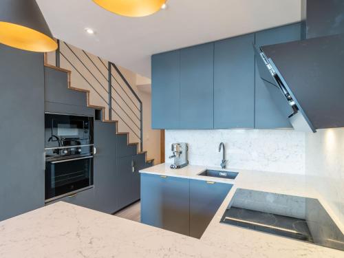 a kitchen with blue cabinets and a staircase at Apartment Les Hauts du Val Claret - Val Claret-23 by Interhome in Tignes