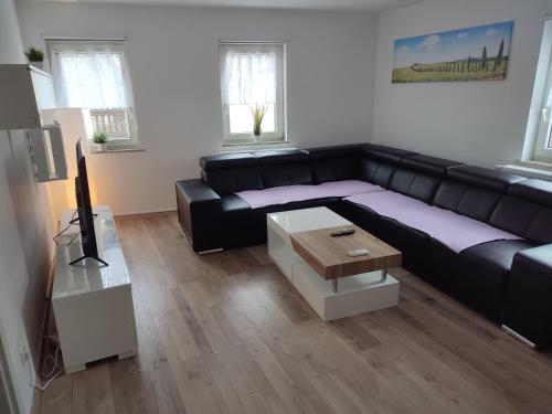 ein Wohnzimmer mit einem schwarzen Sofa und einem Tisch in der Unterkunft Ferienwohnung Südpfalz in Weingarten