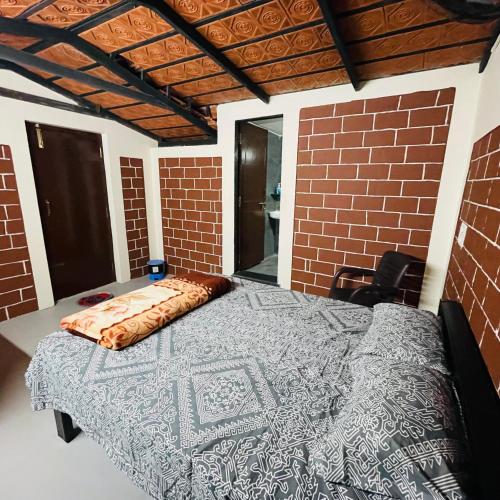 Cama en habitación con pared de ladrillo en Dharani Home Stay, en Badami