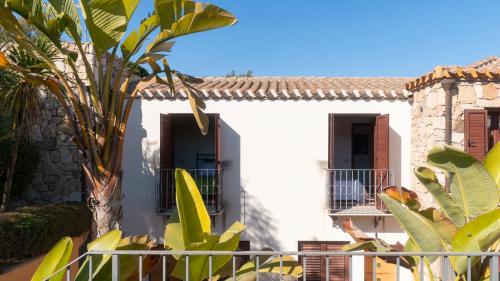 a white building with a palm tree in front of it at Welcomely - Sa Perda in Tortolì