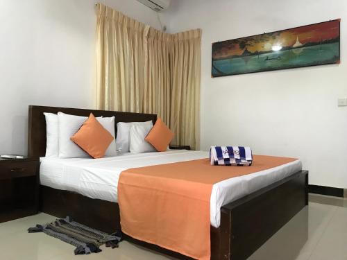 1 dormitorio con 1 cama grande con manta naranja en Paris Garden Resort en Trincomalee