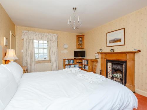a bedroom with a large white bed and a fireplace at The Old School House in Oldshore