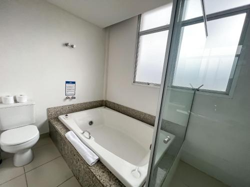 a bathroom with a bath tub and a toilet at Nobile Hotel Belo Horizonte in Belo Horizonte