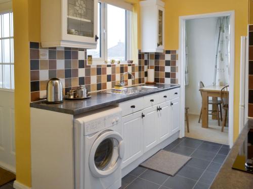 a kitchen with a washing machine and a sink at Longstone in Poundstock