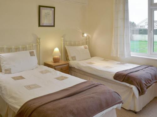 two twin beds in a room with a window at Longstone in Poundstock