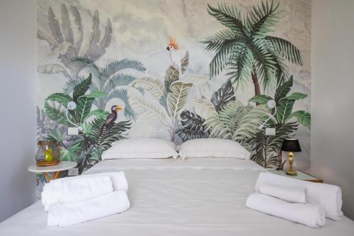 a bedroom with a white bed with a tropical wallpaper at Gallo Fino in Ricadi