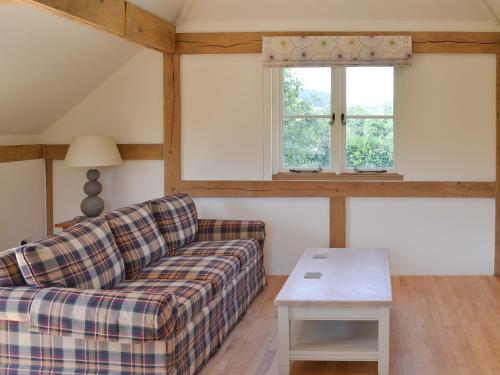 a living room with a couch and two windows at The Piglet in Sidbury