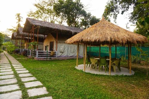 uma casa com uma mesa e cadeiras em frente em Kaziranga Eco Camp em Hatikhuli