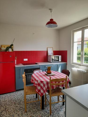 une cuisine avec une table et un mur rouge dans l'établissement La maison aux volets bleus, à Le Vigean