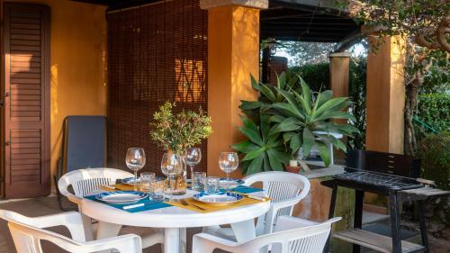 a table with wine glasses and white chairs on a patio at Welcomely - Sa Perda in Tortolì