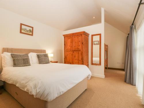 a bedroom with a large bed and a wooden cabinet at Honeysuckle Cottage in Worcester