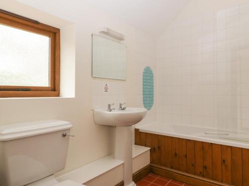 a white bathroom with a sink and a bath tub at Honeysuckle Cottage in Worcester