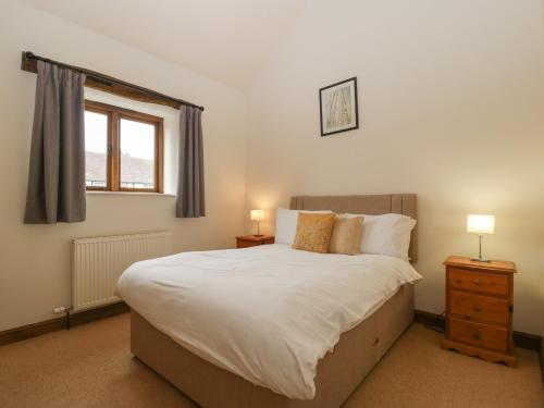 um quarto com uma grande cama branca e 2 candeeiros em Cinder Cottage em Worcester