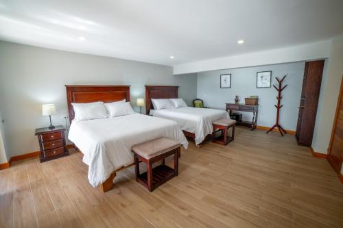 Habitación de hotel con 2 camas y 2 mesas en Flower’s Paradise Monteverde, en Monteverde