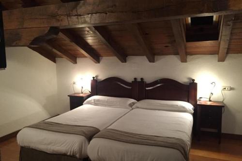 a bedroom with a large bed with two night stands at MAITETXU HABITACION in Viscarret-Guerendiáin