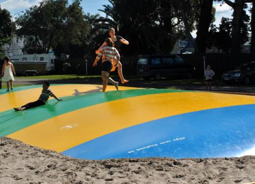 a woman standing on top of a surfboard on a beach at Waikanae Beach TOP 10 Holiday Park in Gisborne