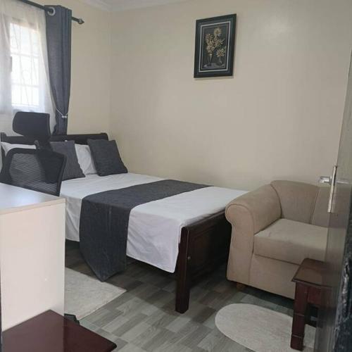 a bedroom with a bed and a couch and a chair at Sharz place in Nairobi