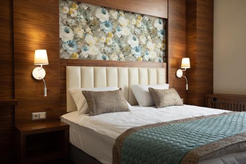 a bedroom with a large bed with a floral painting on the wall at ARDEN PALACE Medical Resort & SPA in Satanov