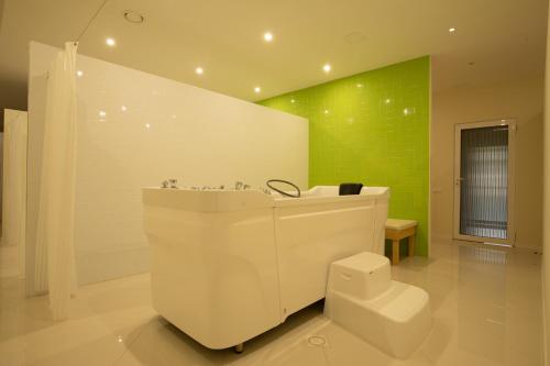 bagno con vasca bianca e parete verde di ARDEN PALACE Medical Resort & SPA a Sataniv