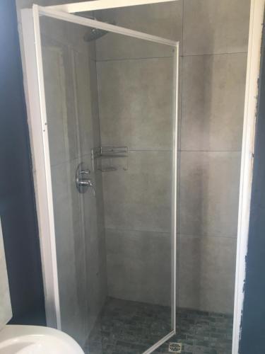 a shower with a glass door in a bathroom at Black Rose Guesthouse in Soweto